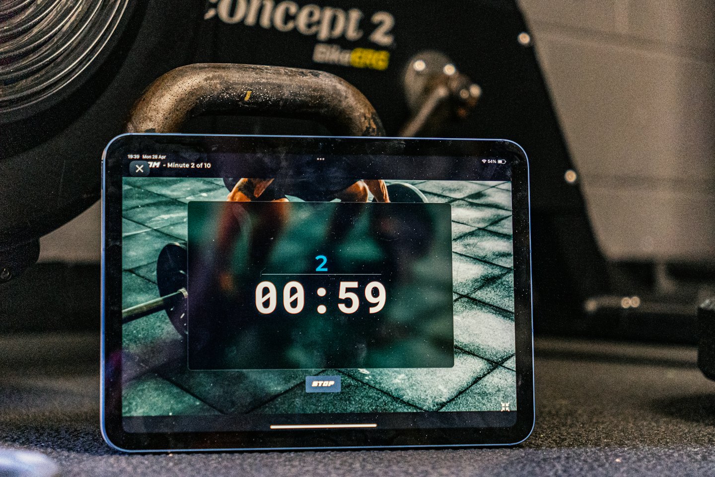Tablet shows workout timer next to exercise bike.